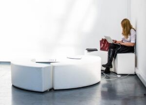 Une femme assise sur un canapé blanc avec un ordinateur portable sur ses genoux, engagée dans une vente.